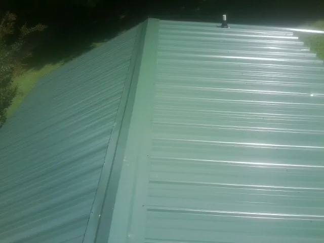 New green metal panels meeting at the ridge of a roof — Flat Roof Repair work by our crew in Eatonville