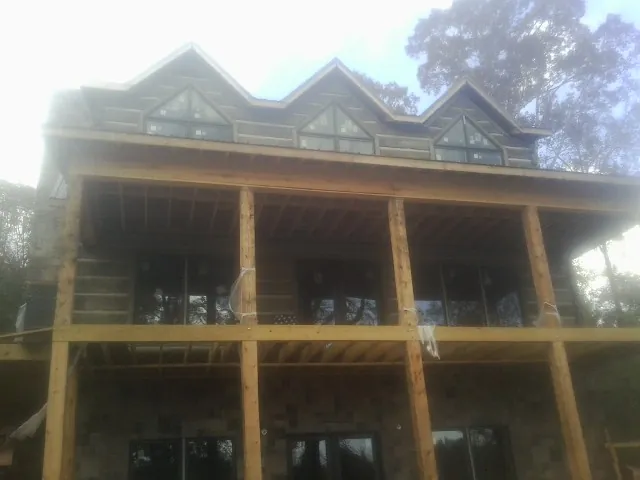 Dormers and porch framing on a large log home under construction — Roof Coating work by our crew in Eatonville
