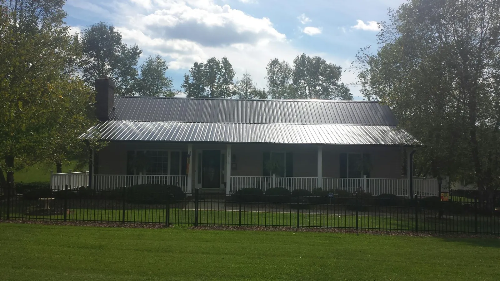 Gray metal roof on a brick ranch with a full width front porch — Gutter Guard Installation work by our crew in Eatonville