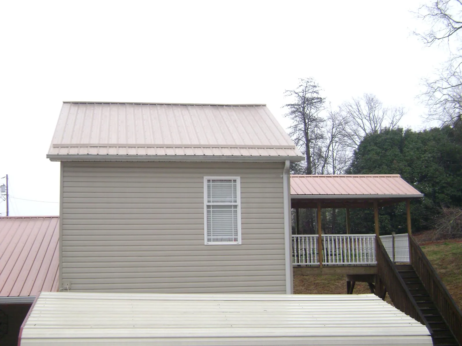 Tan metal roofs on a two story addition and attached porch, from a Roof Replacement job in Eatonville