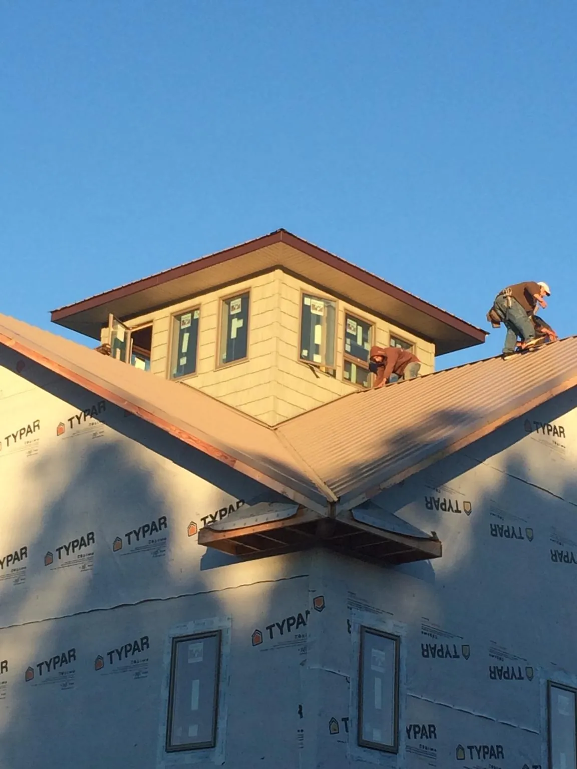 Roofers working around a rooftop cupola on a new metal roof at sunset — Roof Waterproofing in Eatonville by Roofing Brothers